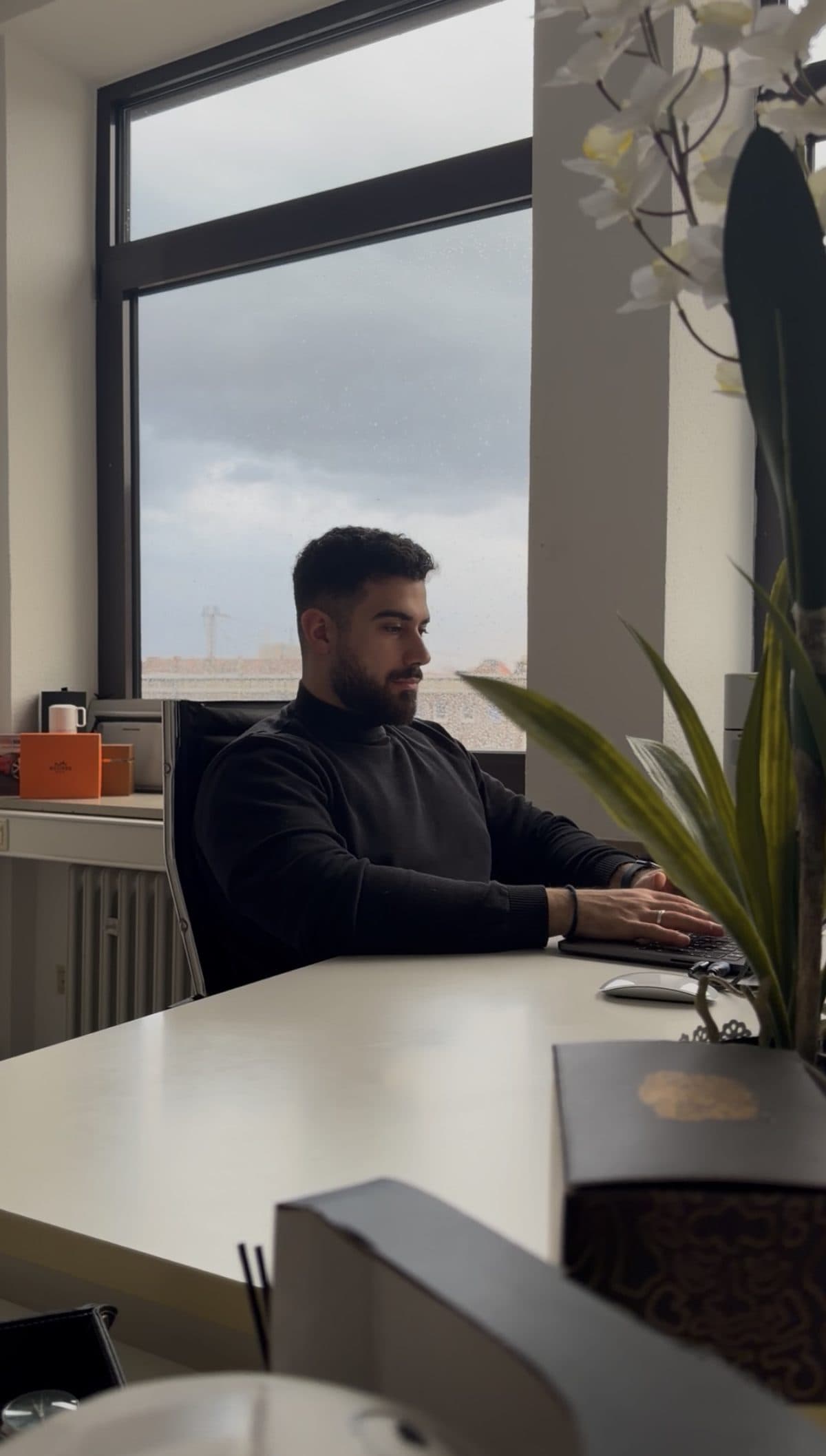 Burak Baris am Schreibtisch im BBR-Büro mit Blick aus dem Fenster